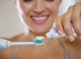 Woman putting toothpaste on toothbrush